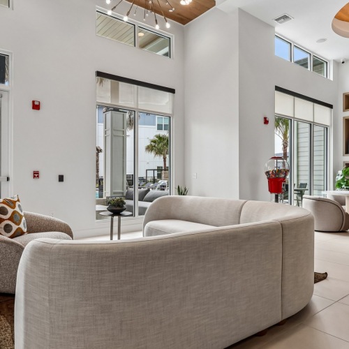 a lounge with a refrigerator, large windows and a rug