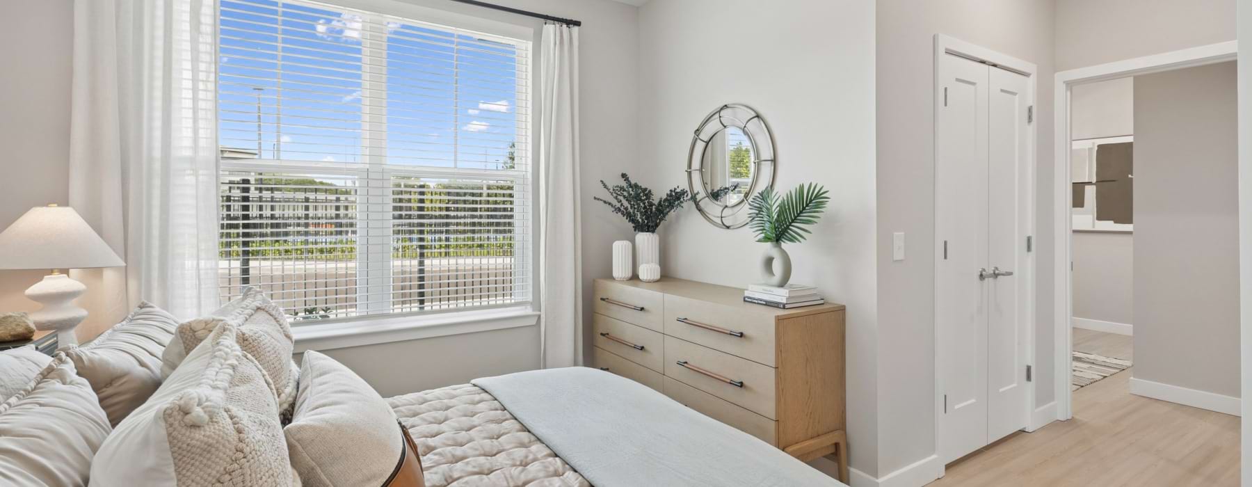 a naturally lit bedroom with a tv, dresser, and bedside tables